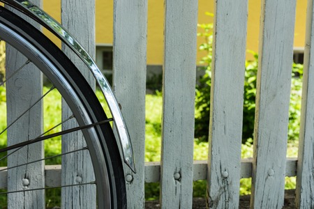 back wheel of bicycle in front of white fenceの写真素材