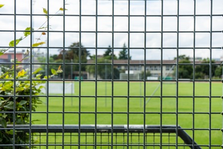 soccer football field seen through iron fence gate