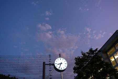 clock with violet sky at sunset and building with lights on dramatic