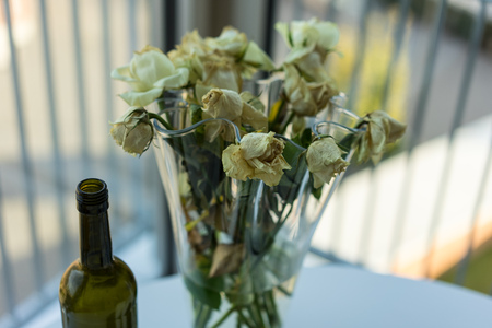 withered yellow roses and wine bottleの写真素材