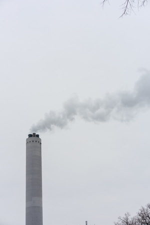 industry chimney with smoke and grey skyの写真素材