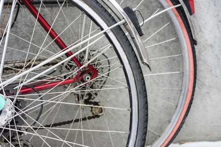 The back wheel of two vintage bicycle parked at a wallの写真素材