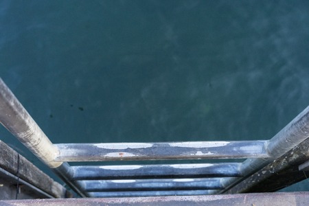 metal stairs leading in to blue waterの写真素材