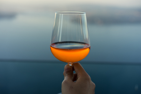 wine glass with drink in front of blue lake iconic backgroundの写真素材