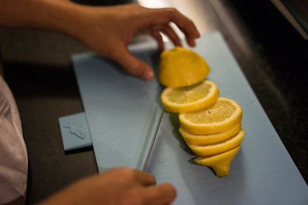 cutting lemon in kitchen with knife and handの写真素材
