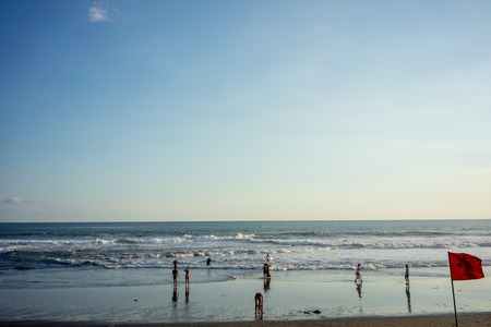 people on ocean beach with waves and warning flagの写真素材