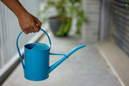 Hand holding blue watering can for urban gardeningの写真素材