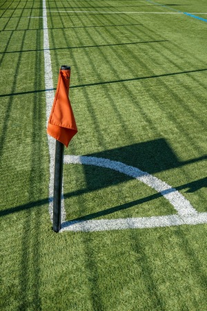 Red corner flag on football or soccer pitch and white lines