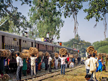 Ajanti, Madhya Pradesh, India-December 23rd, 2008:Local villagers with wood waiting for their train as pairing train waits for croのeditorial素材