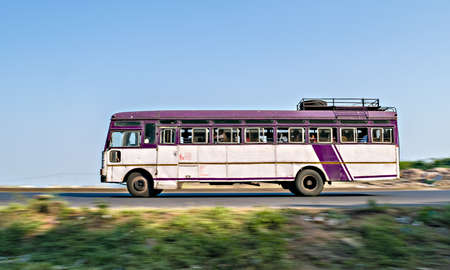 Isolated , slow shutter speed panning image of a speeding state transport bus on highway in Maharashtra, India.のeditorial素材
