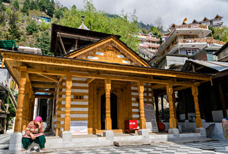 A lady sitting in Sunlight in front of Vashistha temple famous for hot water springs in Manali, Himachal Pradesh, India.のeditorial素材