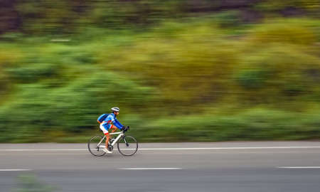 Motion blur, panning image of an isolated  bicycle rider wearing helmet for safety on a way for fitness.のeditorial素材