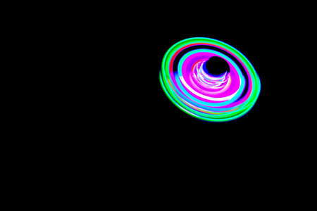 Long exposure photograph of a light spinning top with black background.