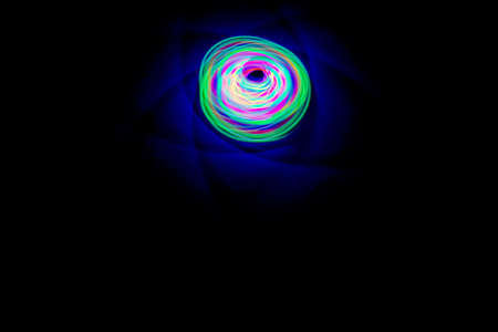 Long exposure photograph of a light spinning top with black background.
