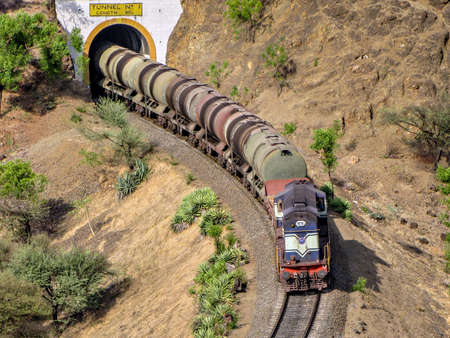 Diesel locomotive hauling a tanker rake through a tunnel on a railway line.