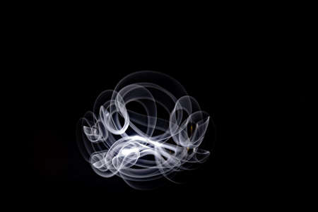 Unique, long exposure, white Led light painting photograph of abstract pattern on black background.