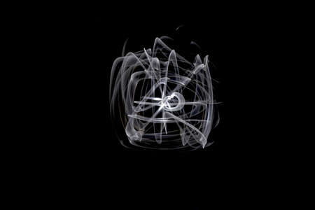 Unique, long exposure, white Led light painting photograph of abstract pattern on black background.