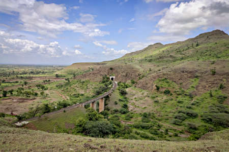 Single railway line passing through tunnel in the hill with nice blue clouds background.の写真素材