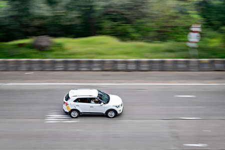 Lonavala,Maharashtra,India-October 2nd,2018: Background blur , selective focus, pan image of a fast moving white car on Pune-Mumbai expressway.のeditorial素材