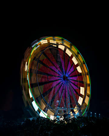Fun fair Giant Colorful Ferris wheel spinning at night. Slow shutter image of a rotating giant wheel at night.の写真素材