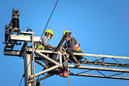 Pune,Maharashtra, India - February 3rd, 2022: Construction workers fixing overhead electrical cables of Pune Metro project.のeditorial素材
