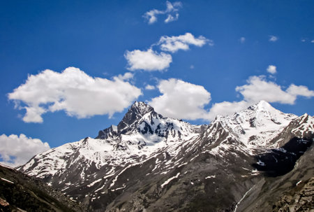 Snow clad mountains with white clouds in blue sky background on way to Leh.の写真素材