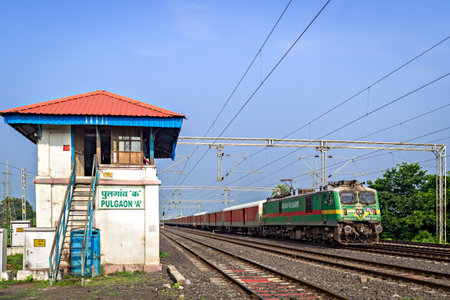 Electric loco powered parcel train , passing past the old signal cabin at Pulgaon. Translation of...
