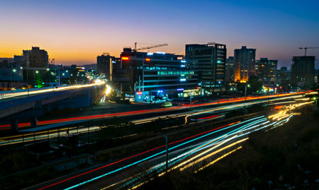 Pune, Maharashtra, India-March 25th, 2023:Slow shutter speed image of light trails, beautiful sunset sky , buildings and flowing traffic on motorway.のeditorial素材