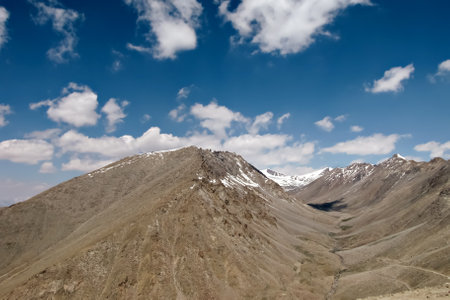 Snow clad mountains with white clouds in blue sky background on way frpm Manali to Leh.の写真素材