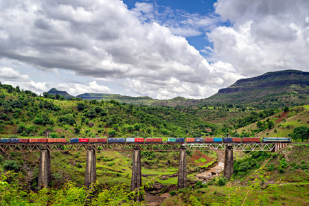 Igatpuri, Maharashtra, India-June 26th, 2022: Colorful container train crosses old viaduct at scenic location.のeditorial素材