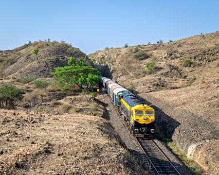 Goods train coming out of a huge hill cutting in Ambale, Maharashtra, India.の写真素材