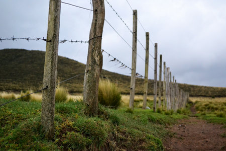 Rustic fence with barbed wire on rural mountain landscape.の写真素材