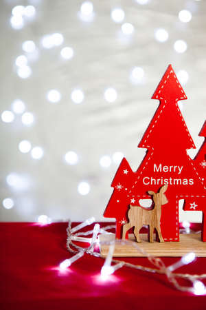 red decoration Christmas tree and fawn from the tree of the Christmas table on the background of Christmas lights bokehの写真素材