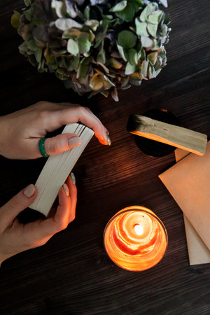 tarot cards in hands on a dark background in the light of a candle