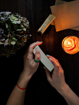 tarot cards in hands on a dark background in the light of a candleの写真素材