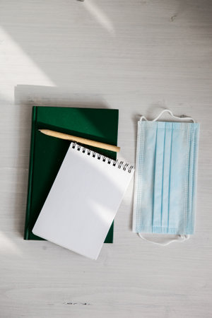 an open white notebook on a green diary, an eco-friendly pen on a light background, a medical mask and a branch of greeneryの写真素材
