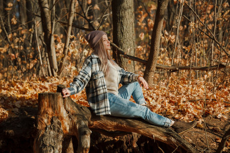 a blonde girl in a plaid shirt in the autumn forestの写真素材