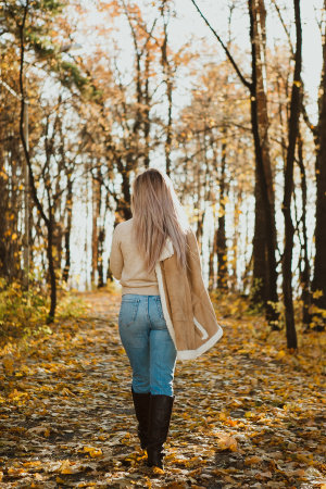 a blonde adult girl walks in the autumn forest. a walk in the fresh air aloneの写真素材