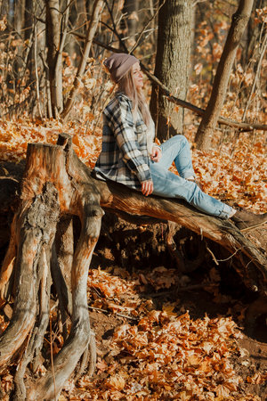 a blonde girl in a plaid shirt in the autumn forestの写真素材