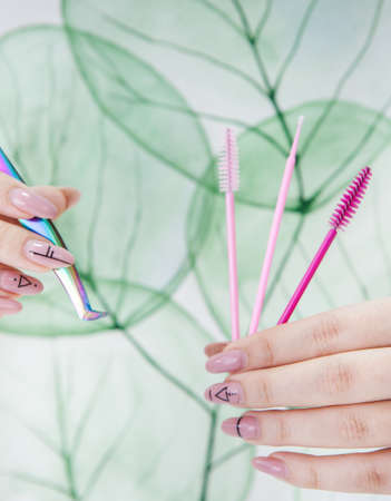 tools for eyelash extensions in hands on a background with a natural patternの写真素材