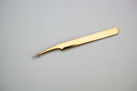 tools for eyelash extensions and eyebrow design. cosmetic tweezers in gold color on a white backgroundの写真素材
