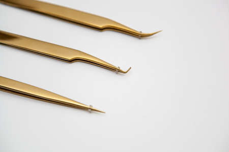 tools for eyelash extensions and eyebrow design. cosmetic tweezers in gold color on a white backgroundの写真素材