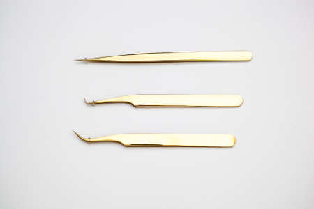 tools for eyelash extensions and eyebrow design. cosmetic tweezers in gold color on a white backgroundの写真素材