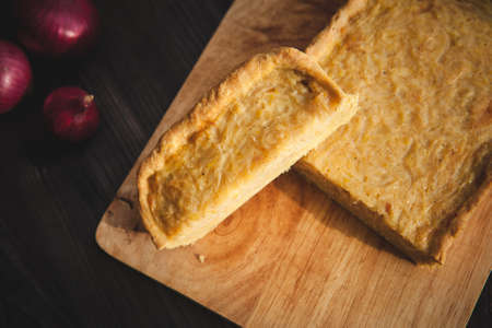 french onion cake on dark wooden background with red onionsの写真素材