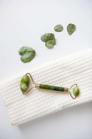 green jade facial massage roller on white towel, facial spa, home careの写真素材
