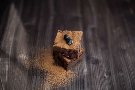 brownie cake on a dark background decorated with fresh berries