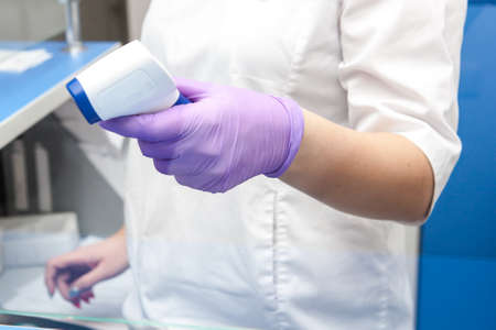 the doctor measures the temperature of the hand remotely