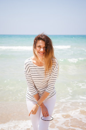 european girl having fun on the sea beach. a girl in light clothes in the open sun on vacation
