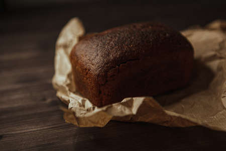 freshly baked black rye bread on a dark background and on craft paper. Dark moody background with free text space. top viewの写真素材