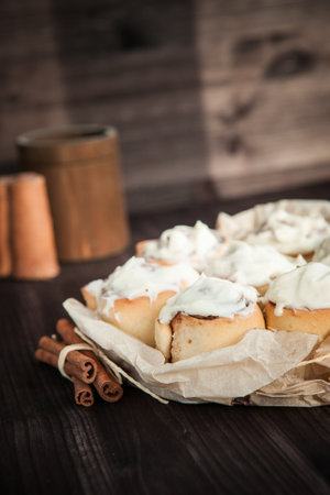 fresh cinnamon rolls and cream on a wooden background, cinnamon sticks. home madeの写真素材